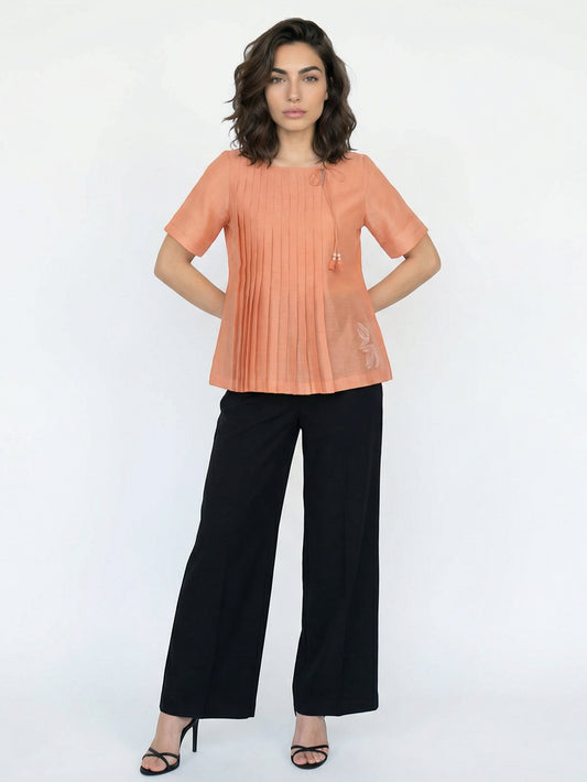 Seen Unseen orange cotton pleated top with tassel ties and subtle embroidery, short sleeves, pair it with black wide-leg trousers.
